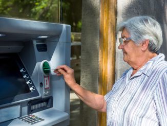 Seniorin hebt Geld am Automaten ab.