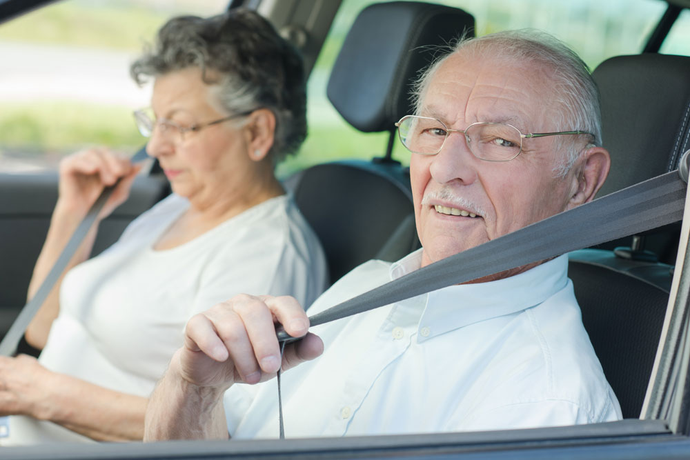 Rentner schnallt sich im Auto an.