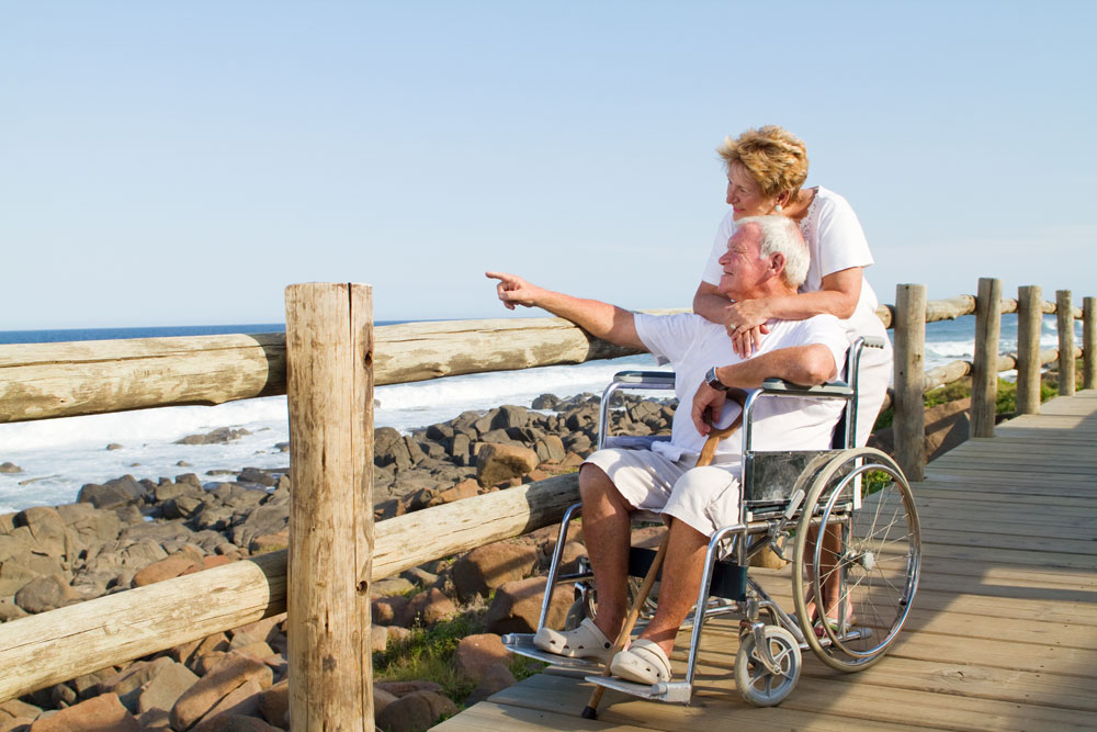 Paar am Strand mit Rollstuhl