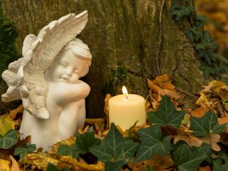 Engel mit Kerze auf Friedhof.