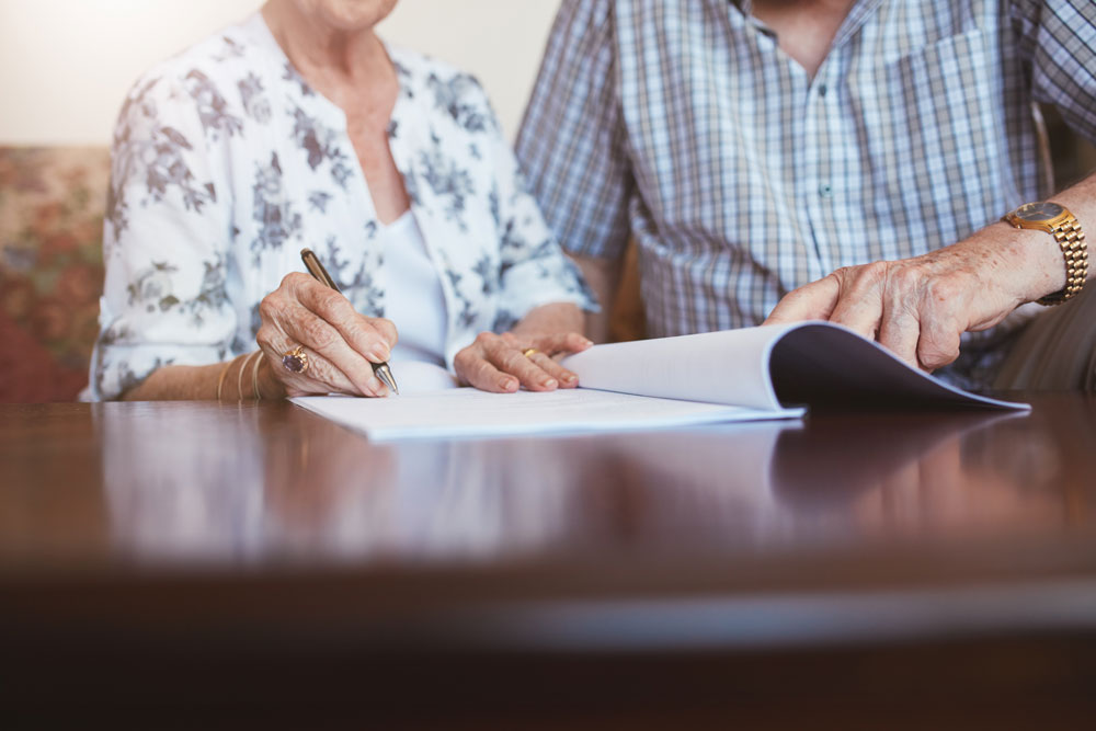 Seniorin unterschreibt Kaufvertrag.